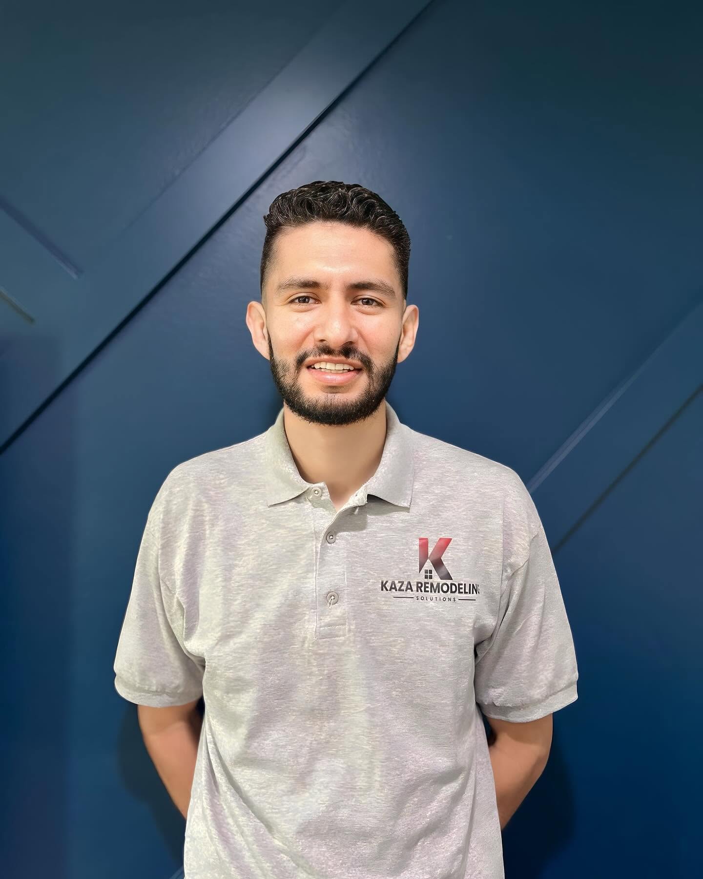 KAZA Remodeling owner in a company polo, standing in front of a navy wood-paneled wall